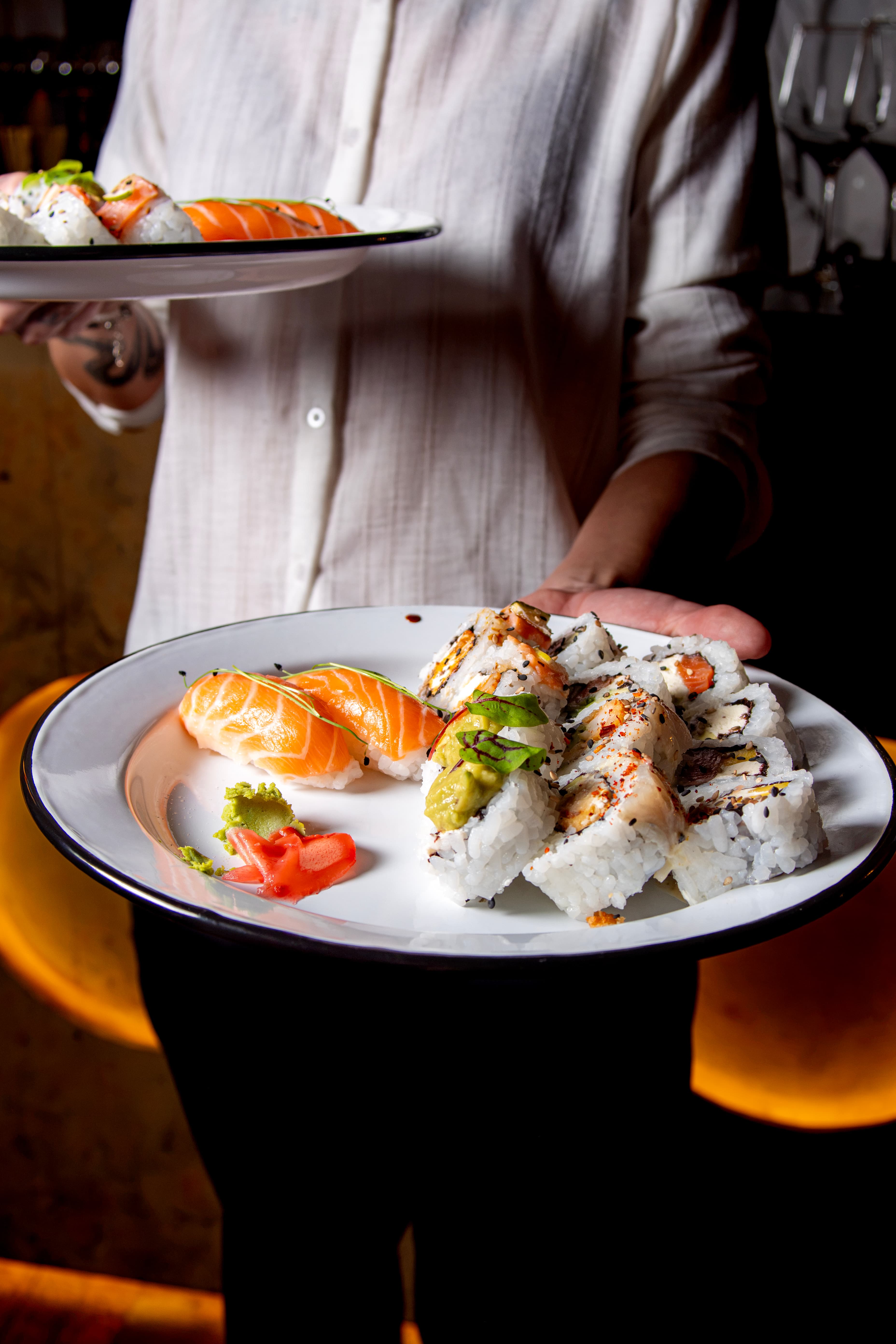 Persona sirviendo dos platos de sushi